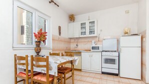 A compact kitchen with white cabinets, a microwave, a stove, and a refrigerator. - Apartments Bozjidar (Stari Grad)