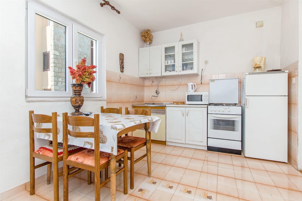 A kitchen with white cabinets, a microwave, a refrigerator, and a dining table with chairs.