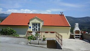 Un petit bâtiment avec un toit recouvert de tuiles rouges, un balcon doté de balustrades et une cheminée.