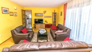A living room with two brown leather sofas, a glass coffee table, and a flat-screen TV. - Apartment Leo (Racisce)