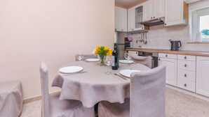 A dining area with a table set for two, a vase with yellow flowers, and a bottle of wine. - Apartment Leo (Racisce)