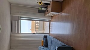 A modern living room with a large window, a sofa, and a framed picture on the floor. - Apartment Anic (Bol)