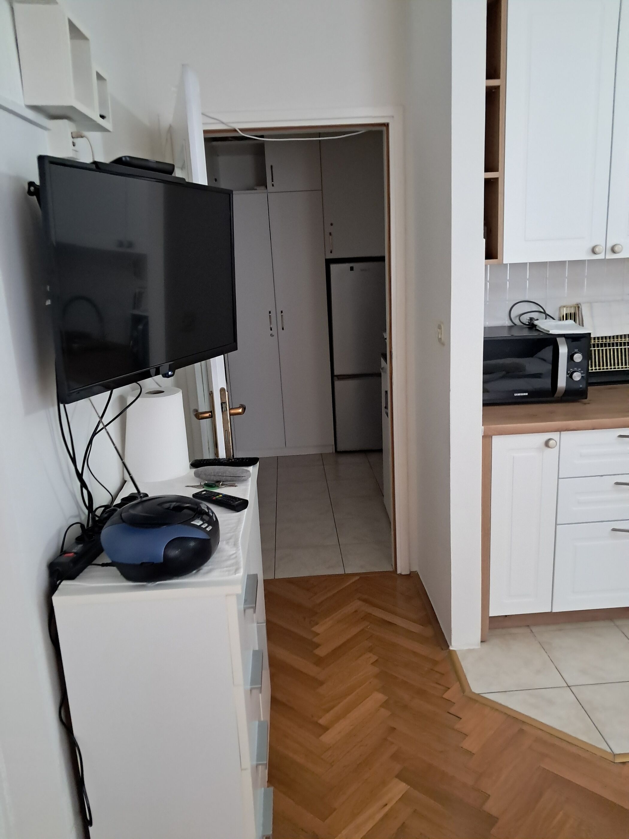 A kitchenette with a microwave, toaster, and a flat-screen TV mounted on the wall.