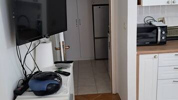 A kitchenette with a microwave, toaster, and a flat-screen TV mounted on the wall.