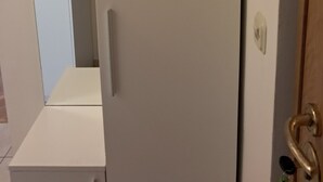 Une pièce avec une armoire blanche, un miroir et une porte en bois dotée d’une poignée en laiton.