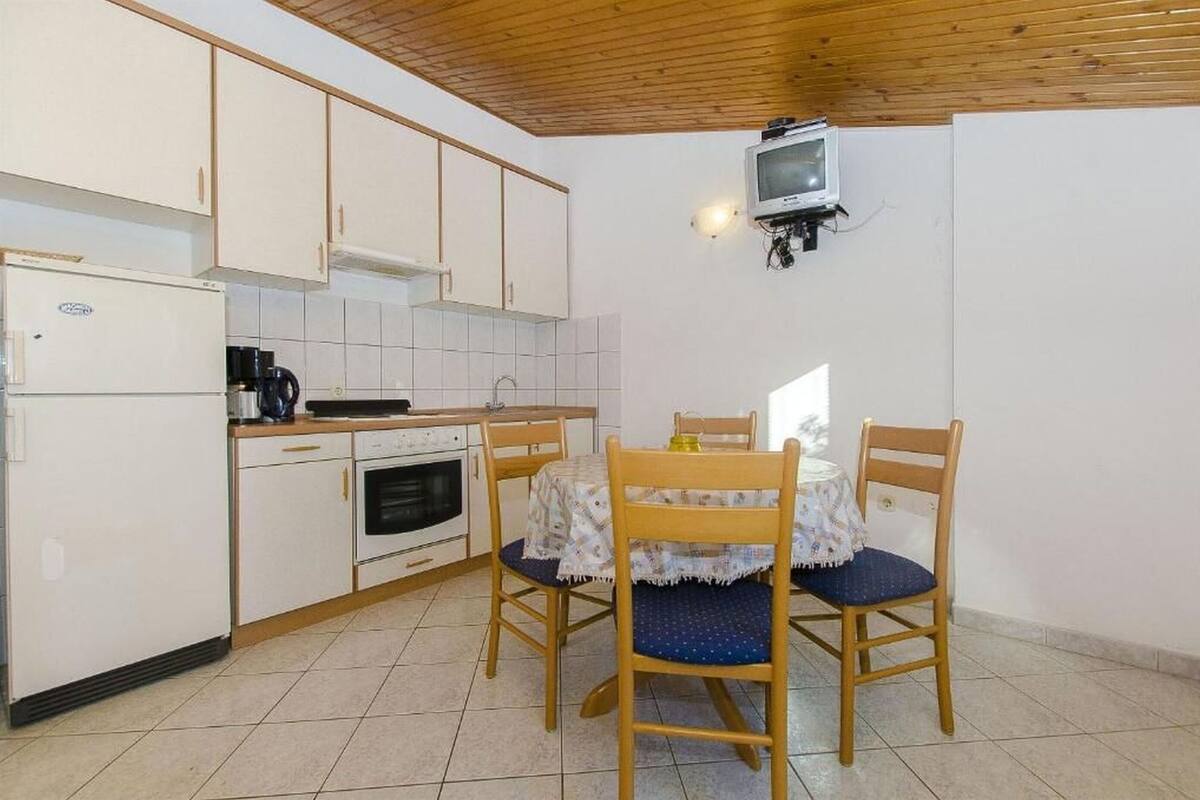 A compact kitchen with white cabinets, a stove, and a dining table with chairs.