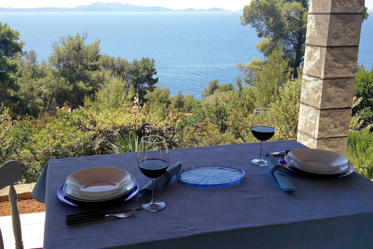 A table set for two with a view of the sea and greenery.