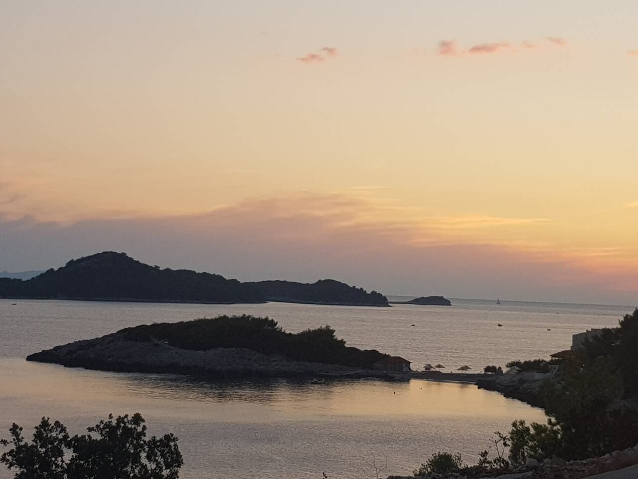 Un paysage côtier avec des eaux calmes, des îles lointaines et un ciel dégagé.