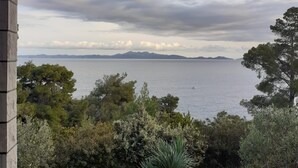 Et overdækket udendørs område med udsigt til havet og fjerne bjerge.