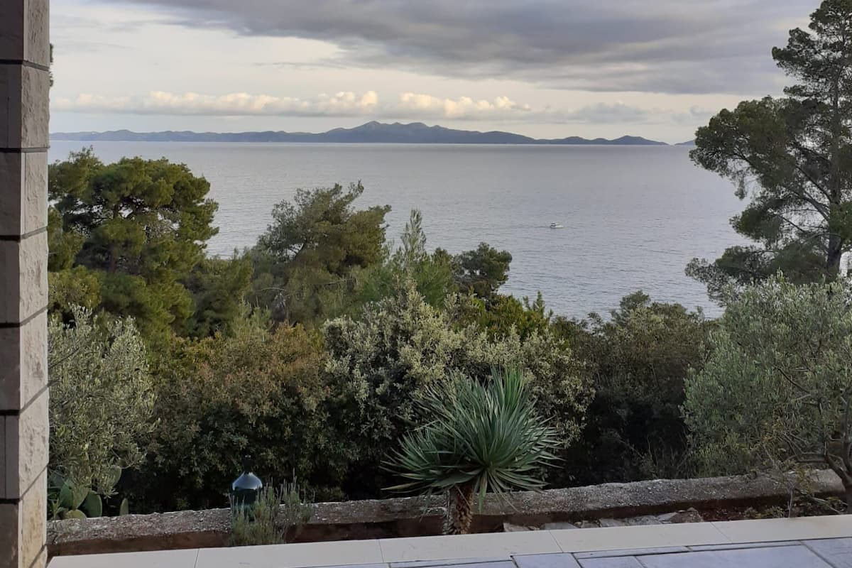 A covered outdoor area with a view of the sea and distant mountains.