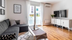 A modern living room with a sofa, a coffee table, a TV, and a sliding glass door leading to a balcony. - Apartment Apartment In Centre For 6 (Split)