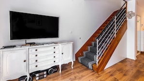 A staircase with wooden steps and a black railing, a white cabinet with drawers, and a flat-screen TV mounted on the wall. - Apartment Apartment In Centre For 6 (Split)