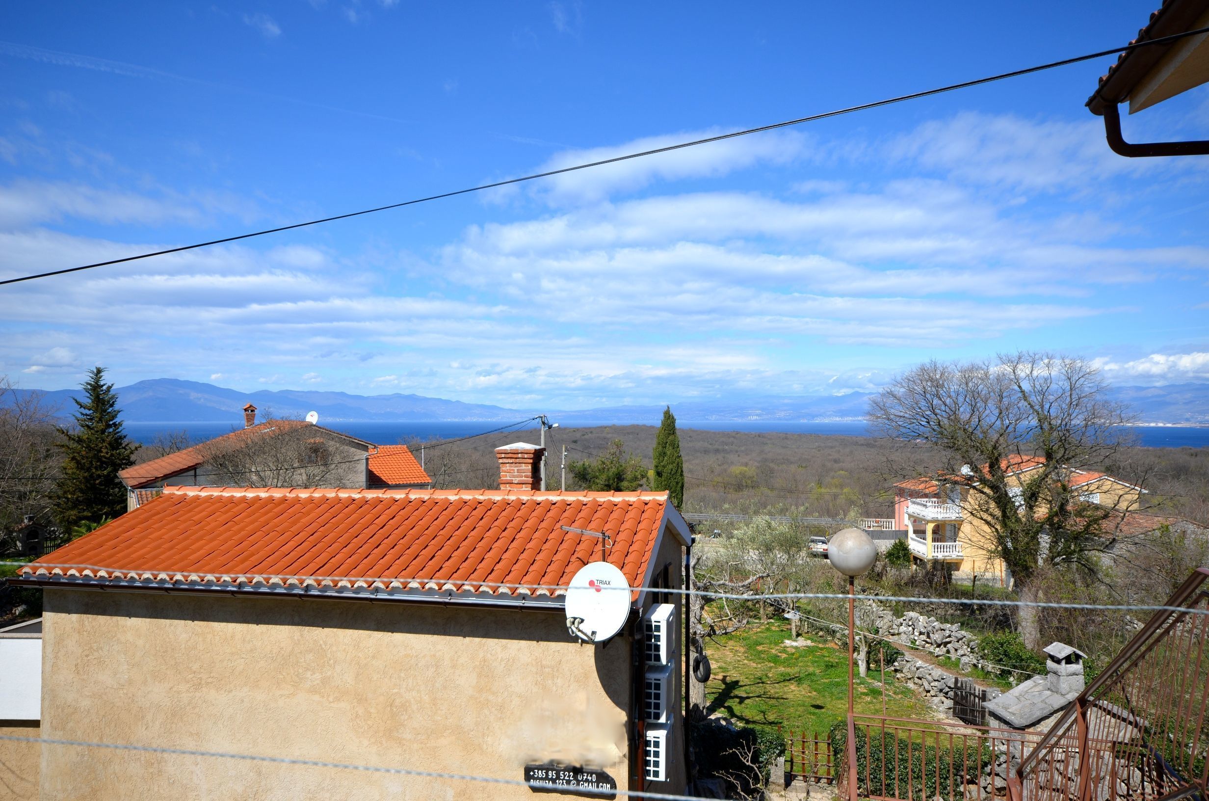 A residential area with houses, a satellite dish, and a clear view of distant mountains.