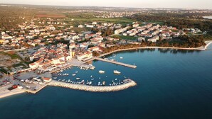 An aerial view of a coastal town with a marina, residential buildings, and a prominent church. - Apartments Armando (Fazana)