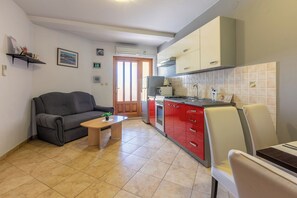 A compact living space with a kitchenette, a sofa, a small table, and a dining area.