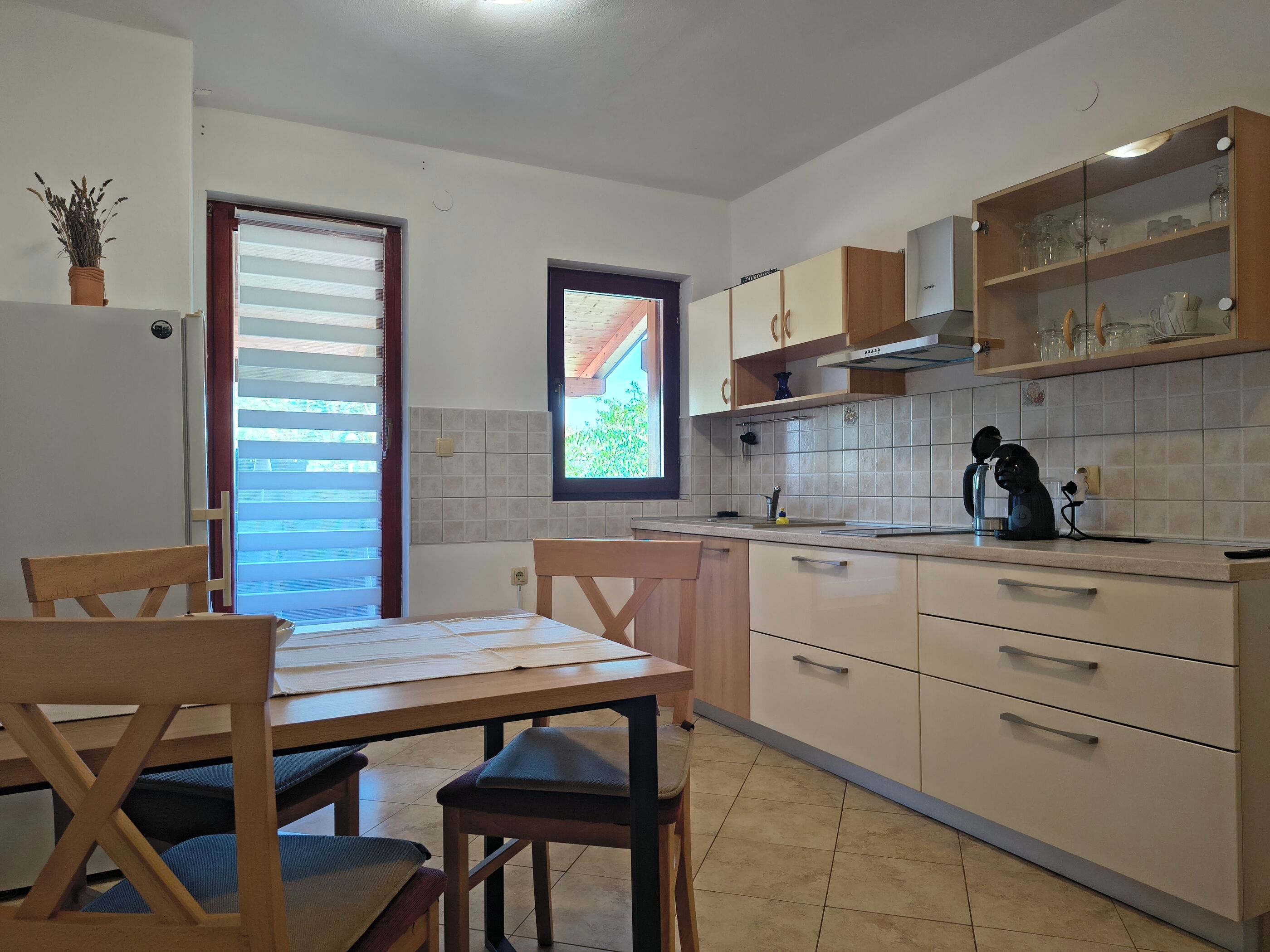 Une cuisine équipée d’une table à manger, de chaises, de placards et d’une fenêtre.