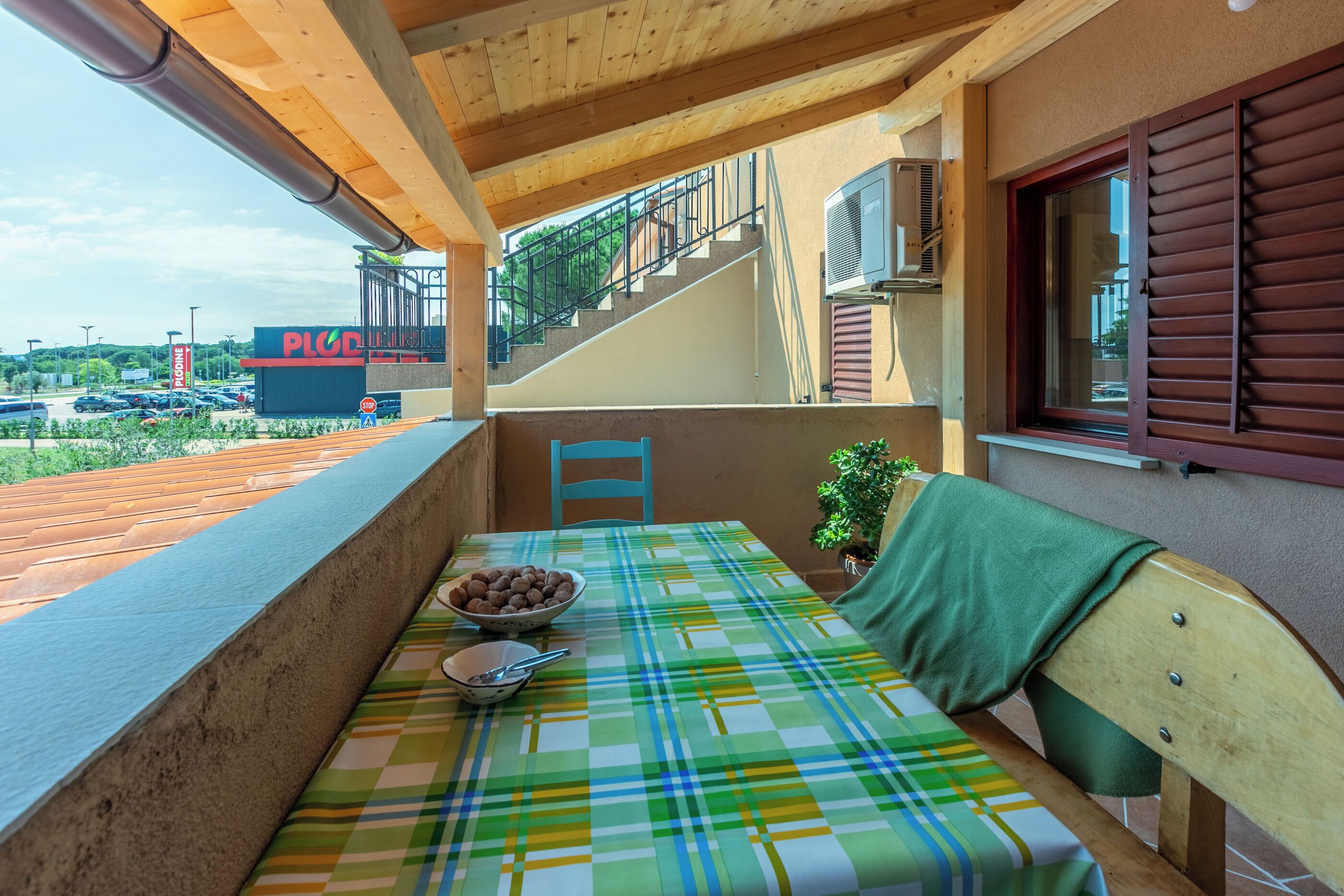 En balkon med et bord dækket til to, en stol og udsigt til en kontorbygning.