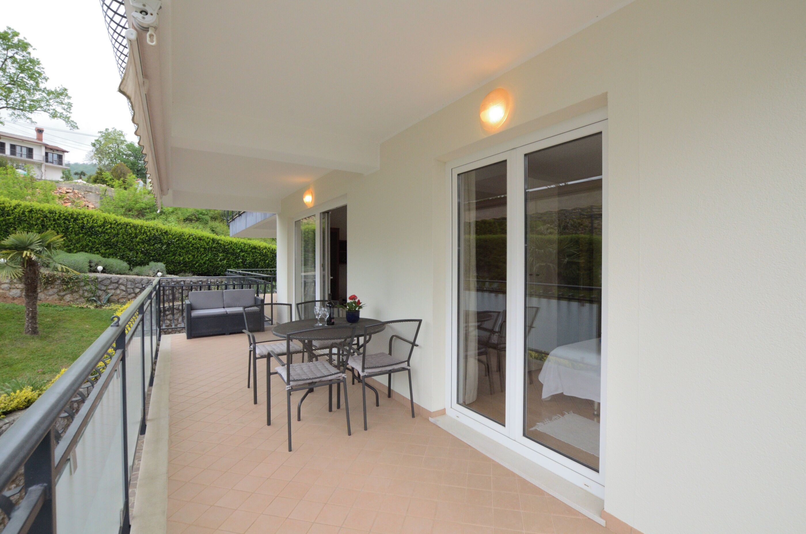 A covered patio area with a table and chairs, a sofa, and a glass door leading to a bedroom.