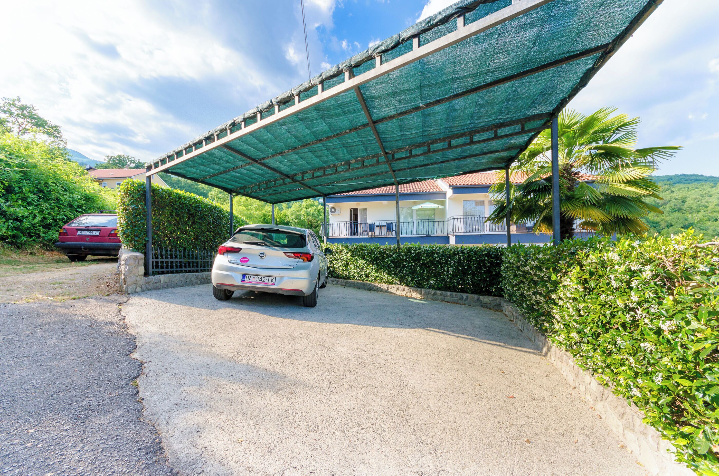 A covered parking area with a car parked under a green canopy.