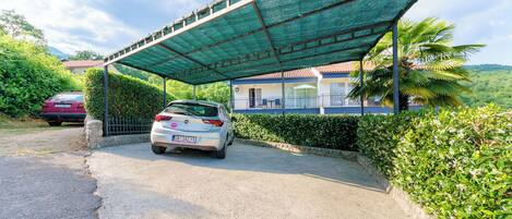 A covered parking area with a car parked under a green canopy.