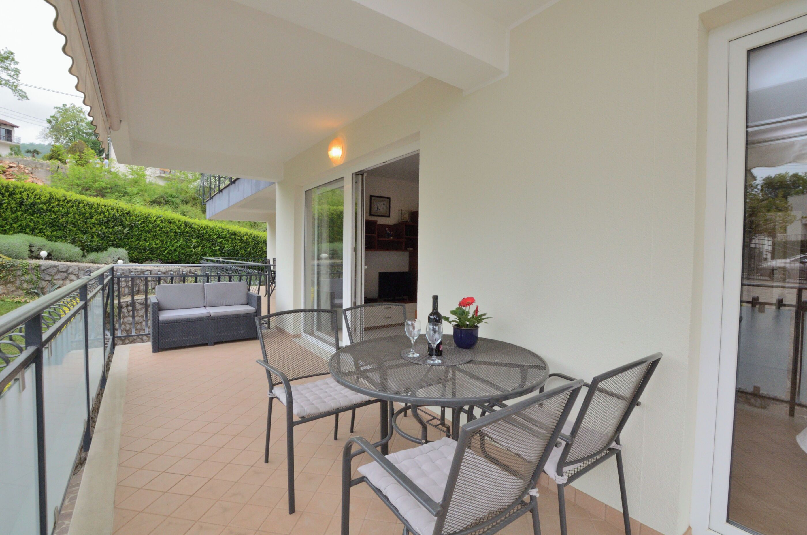 A balcony with a glass door leading to an indoor area, a round table with chairs, and a sofa.