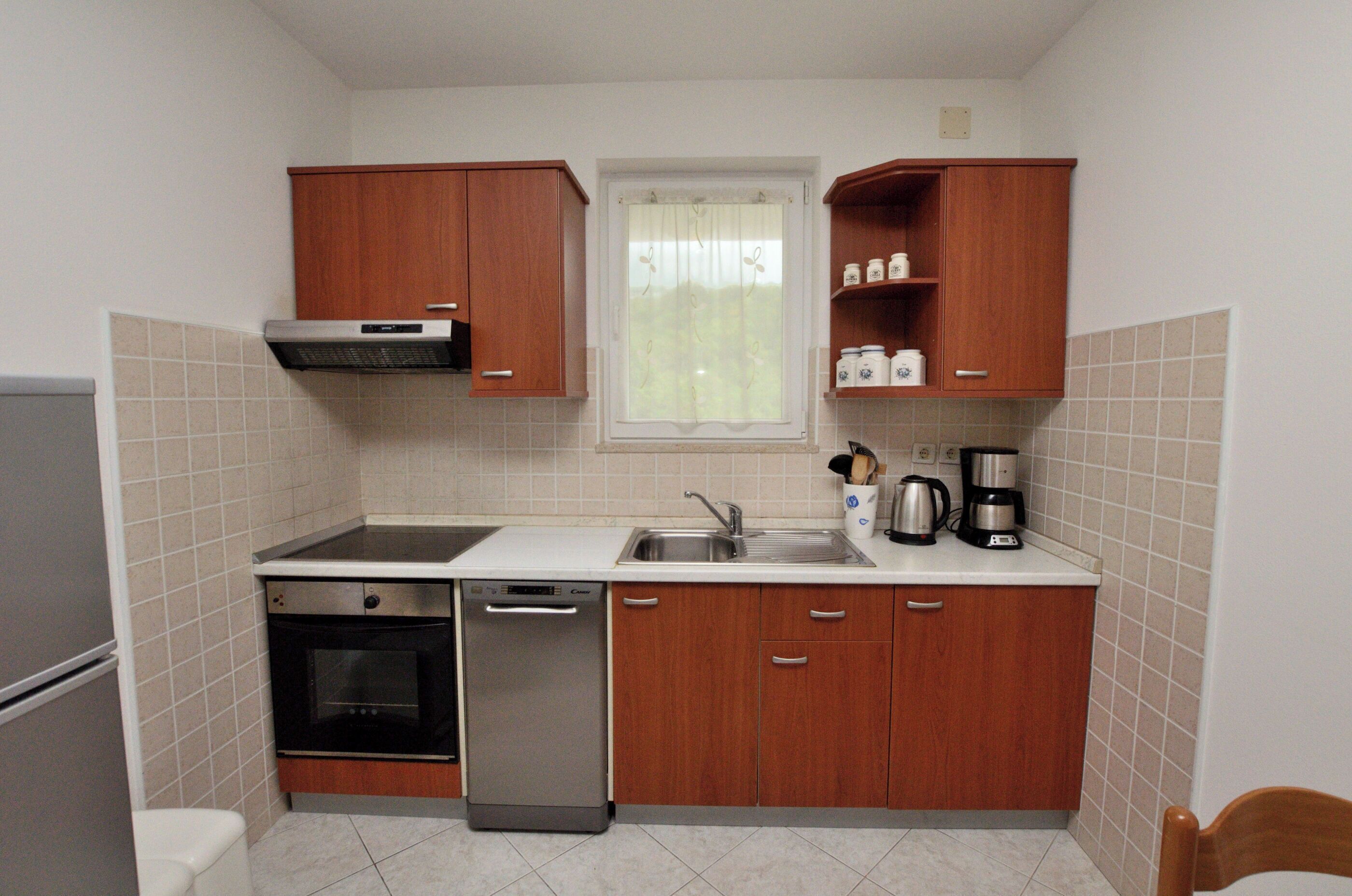 A compact kitchen with a dishwasher, oven, and a coffee maker on the countertop.