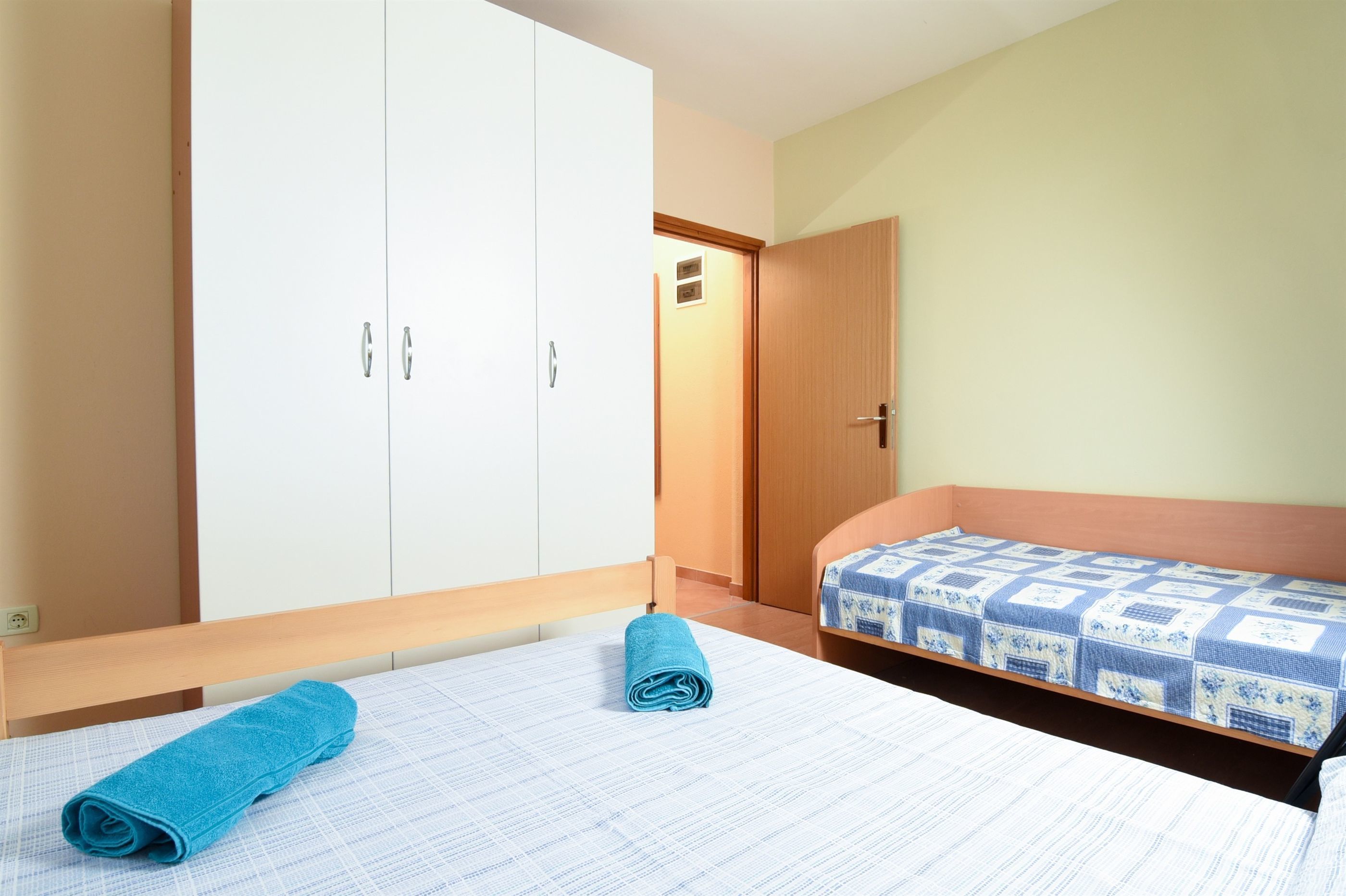 Un dormitorio con una cama, un armario de madera y una puerta que da a otra habitación.