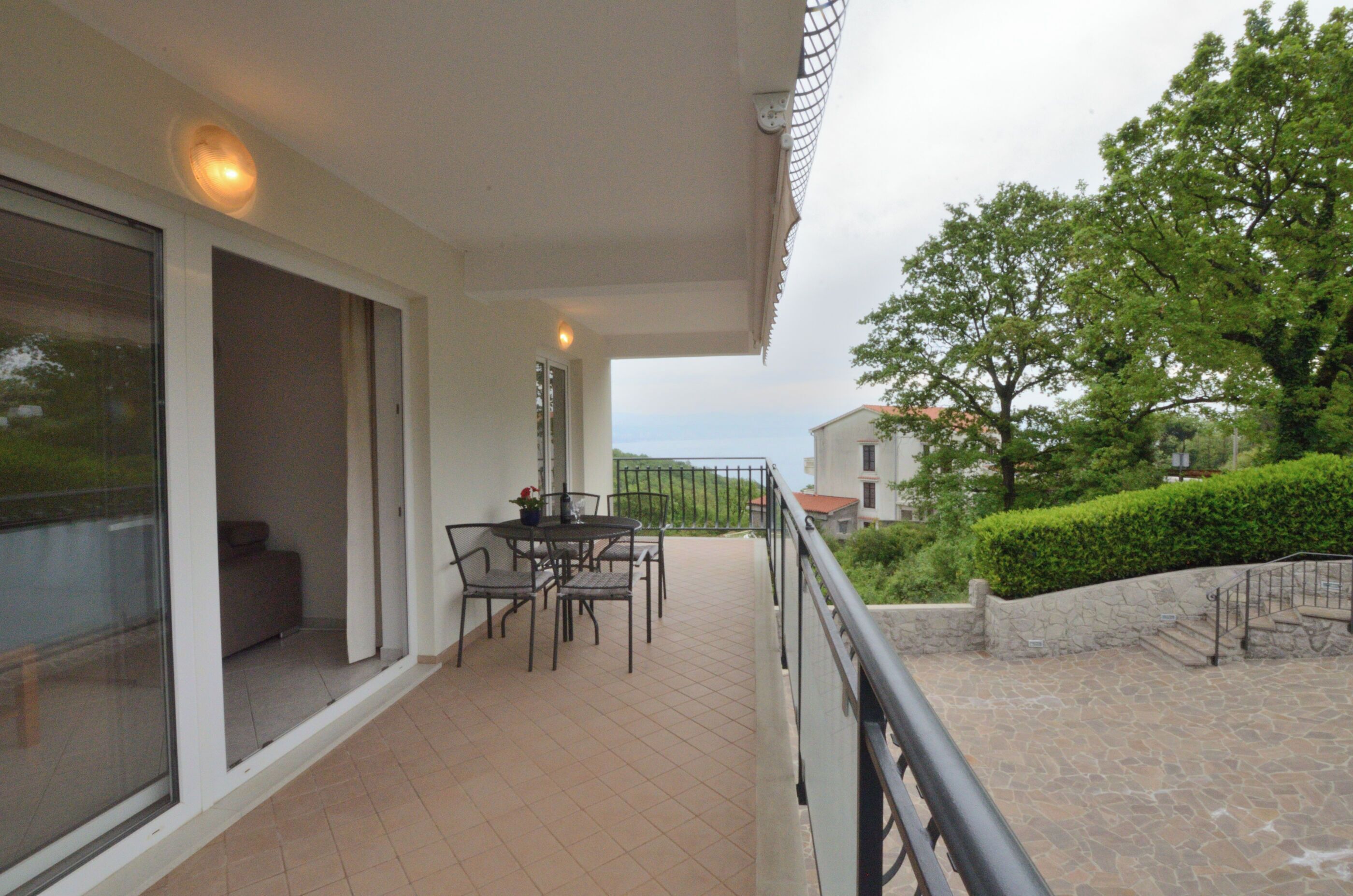 A balcony with a table and chairs, a sofa, and a view of the sea.