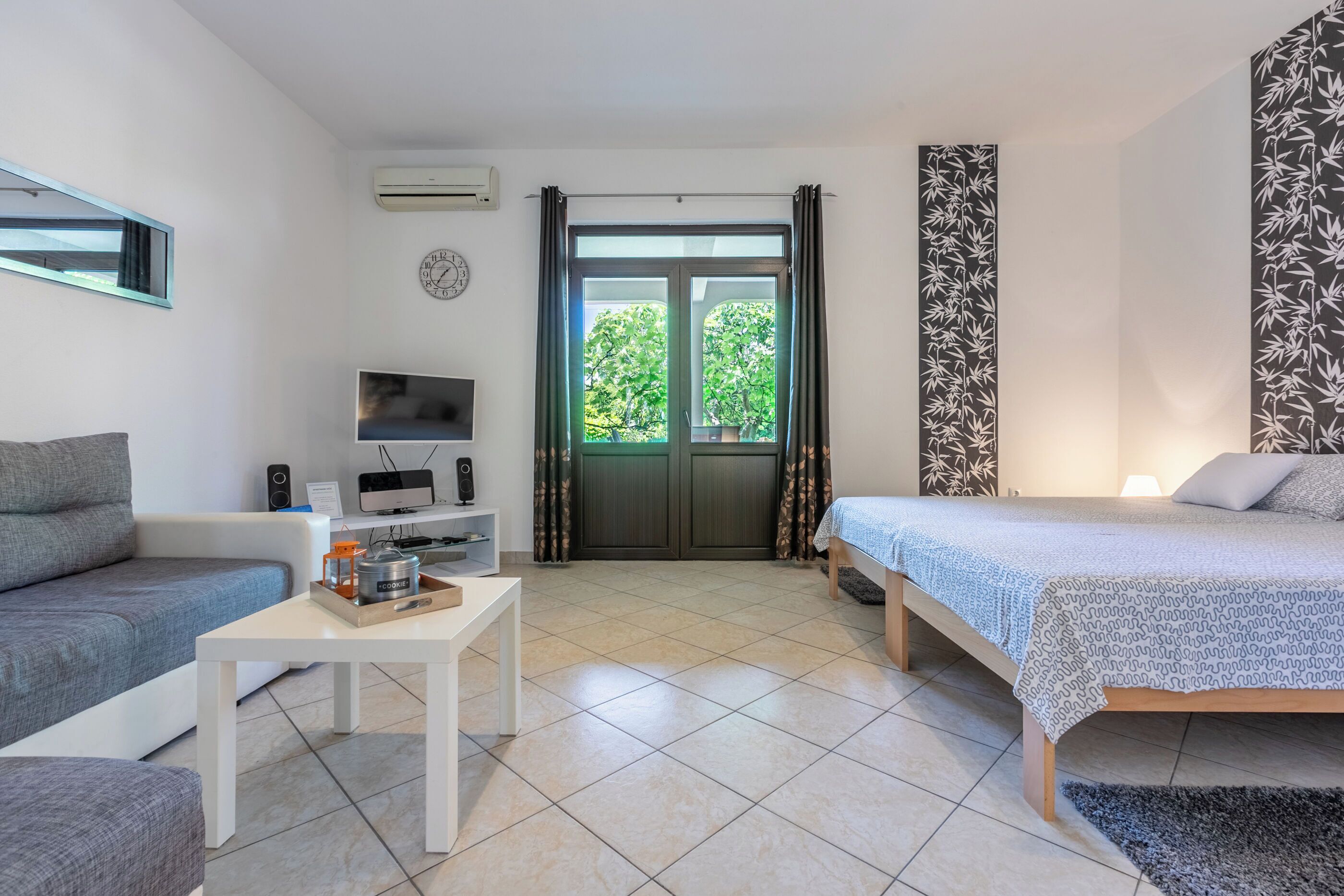A modern room with a bed, a sofa, a TV, and a small table.