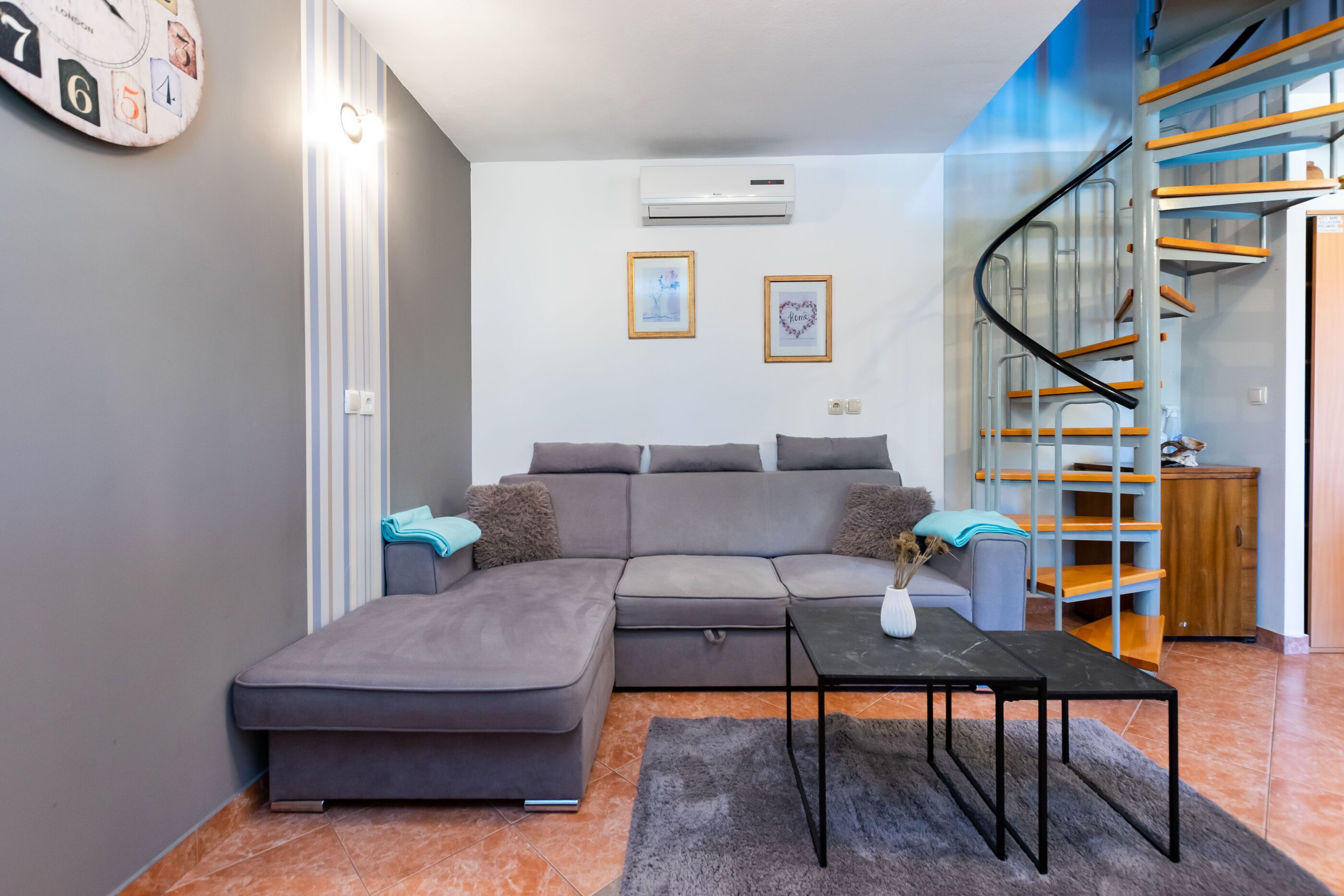 Una sala de estar moderna con un sofá seccional gris, una mesita y una escalera con escalones de madera.