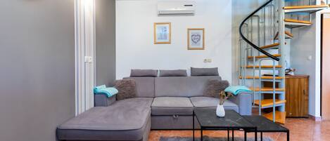 Una sala de estar moderna con un sofá seccional gris, una mesita y una escalera con escalones de madera.