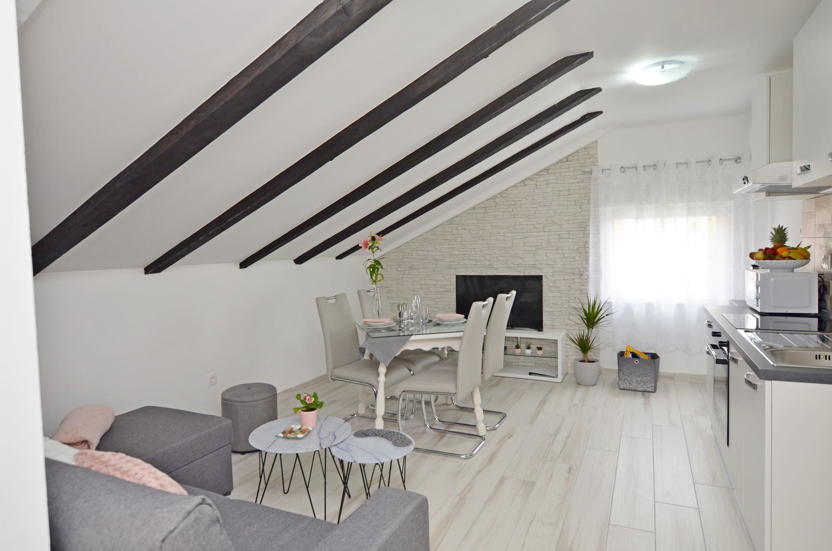 A modern kitchen with a dining area, a sofa, and a small table with a plant.