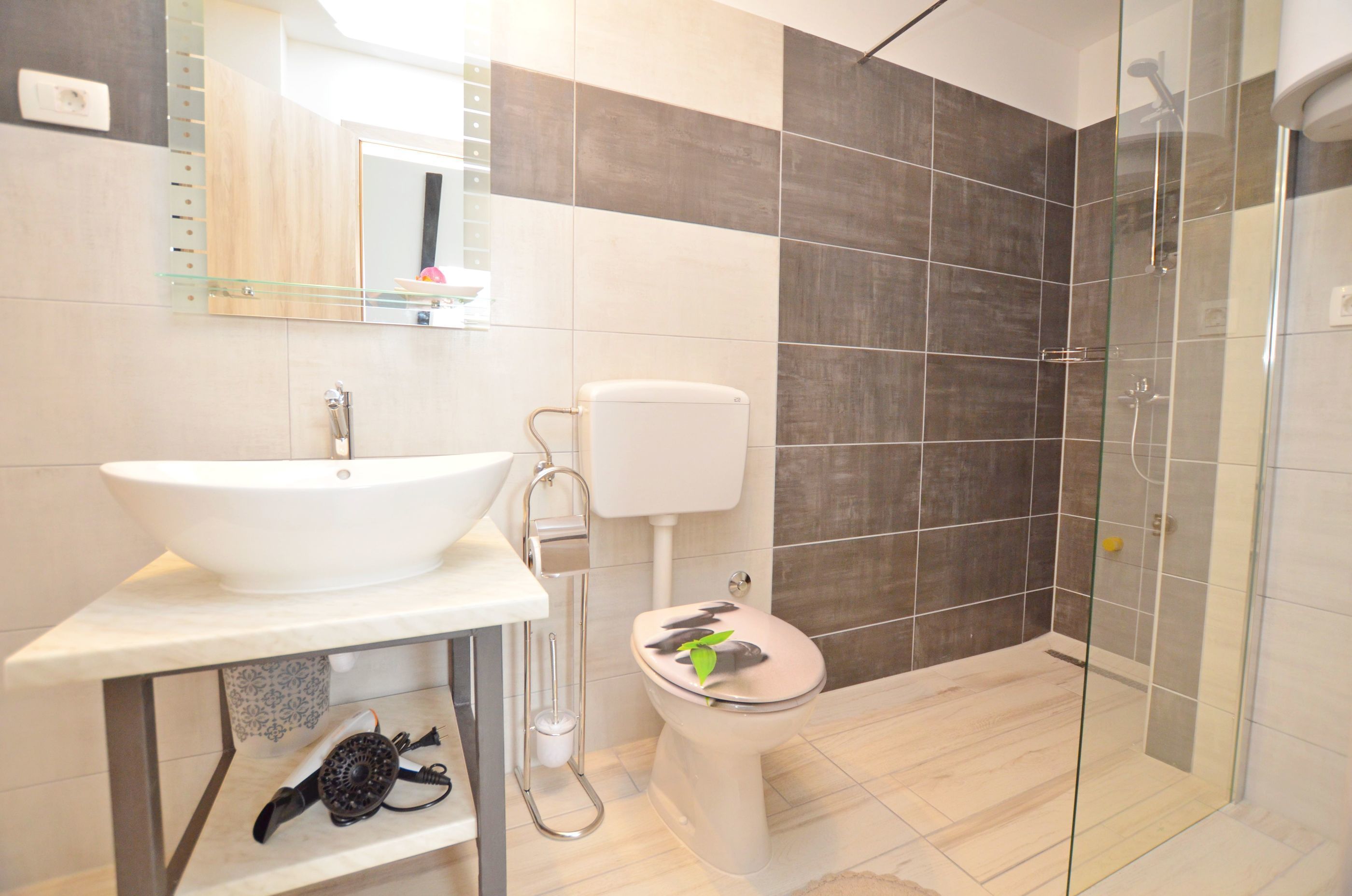 A modern bathroom with a glass shower enclosure, a white sink, and a toilet.