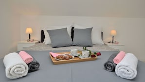 A neatly made bed with pillows, a tray with croissants and cups, and towels on the bed. - Apartments Viktoria (Lovran)