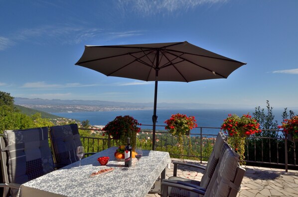 En terrasse med et bord, stole og en parasol med udsigt over et smukt landskab.