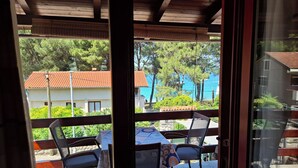 A balcony with a table and chairs, overlooking a residential area with a red-roofed building and trees. - Apartment Paulina (Cres)