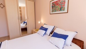 A bedroom with a bed, two pillows, a nightstand, a framed picture, and a wardrobe. - Apartment Paulina (Cres)