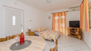 A room with a bed, a TV, a dining table with wine glasses, and a TV stand. - Apartments Danica (Pirovac)
