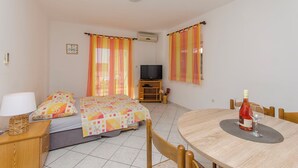 A hotel room with two beds, a TV, a dining table with chairs, and a bottle of wine. - Apartments Danica (Pirovac)
