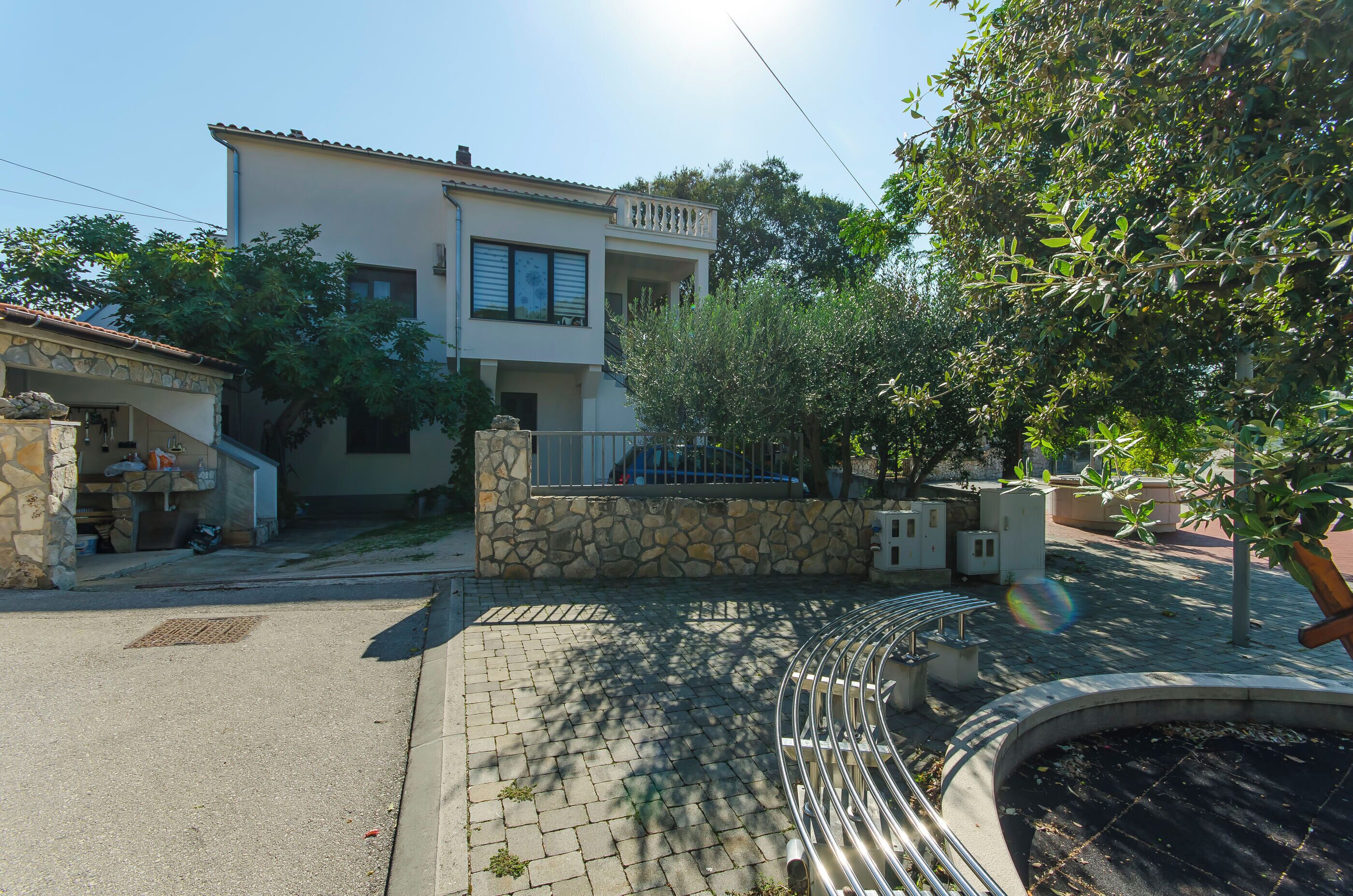Une maison à deux étages avec une façade en pierre, un balcon et une allée pavée.