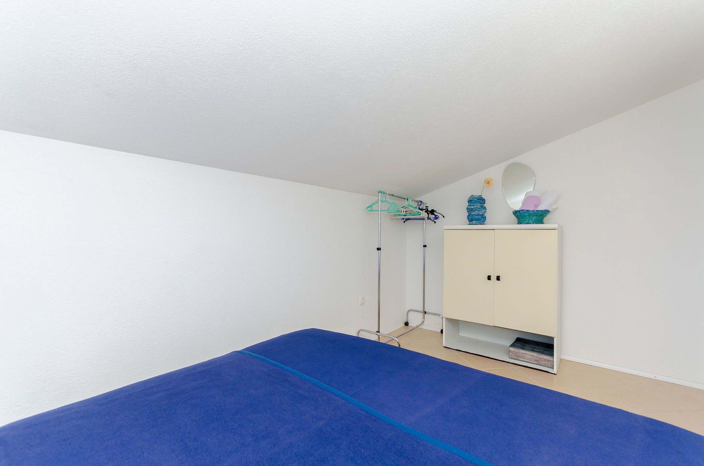 Une pièce avec un tapis bleu, une armoire blanche et un étendoir à linge.