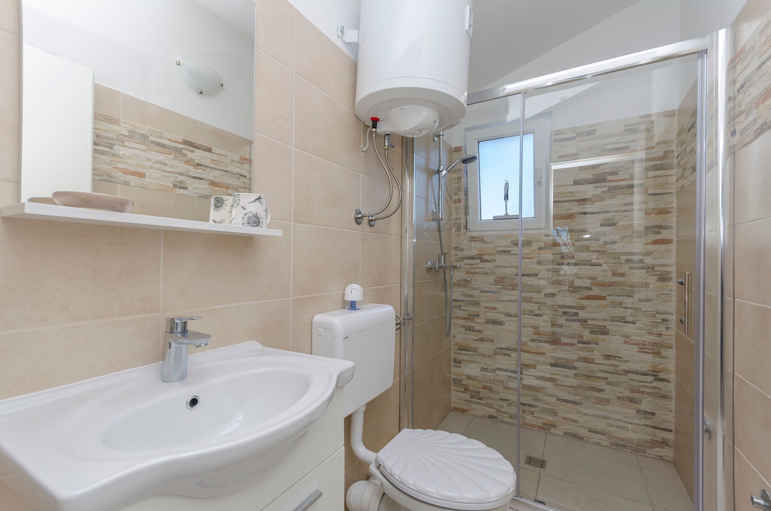 Ein Badezimmer mit weißem Waschbecken, WC und Duschkabine.