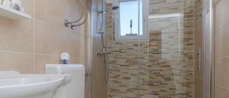 A modern bathroom with a toilet, sink, and shower enclosure.