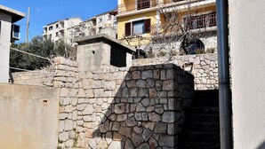 A stone staircase leading to a building entrance, with a clear sky and residential buildings in the background.