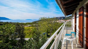 A balcony with a view of a coastal landscape, including a body of water and distant hills. - Apartments Nina (Stinica)