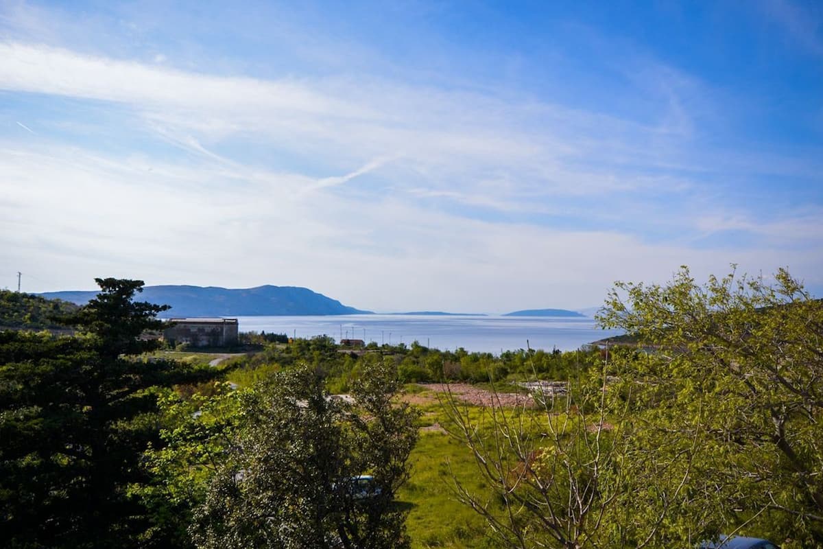 Eine Küstenlandschaft mit freiem Blick auf das Meer und entfernte Berge.