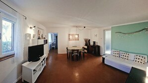 A room with a television, a dining table, a sofa, and a green accent wall. - Apartments Nina (Stinica)