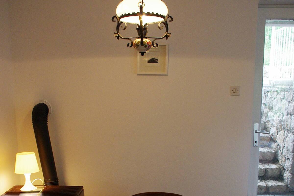 Ein Esstisch mit einer blumigen Tischdecke, einer Schüssel Äpfel und einer Hängelampe.