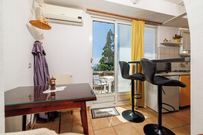 A small kitchen with a dining area, a bar stool, and a sliding glass door leading to an outdoor seating area. - Apartments Jadrana (Novi Vinodolski)