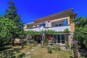 A two-story house with a patio, outdoor furniture, and a garden.